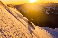 Skier in powder snow at sunset